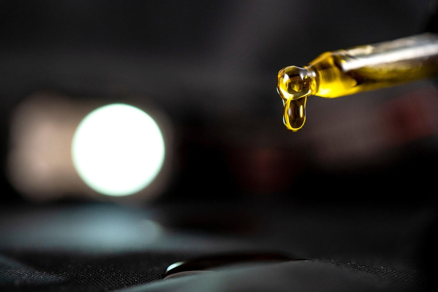 A medicinal dropper releases an amber-colored substance, representing a 7OH concentrate.|