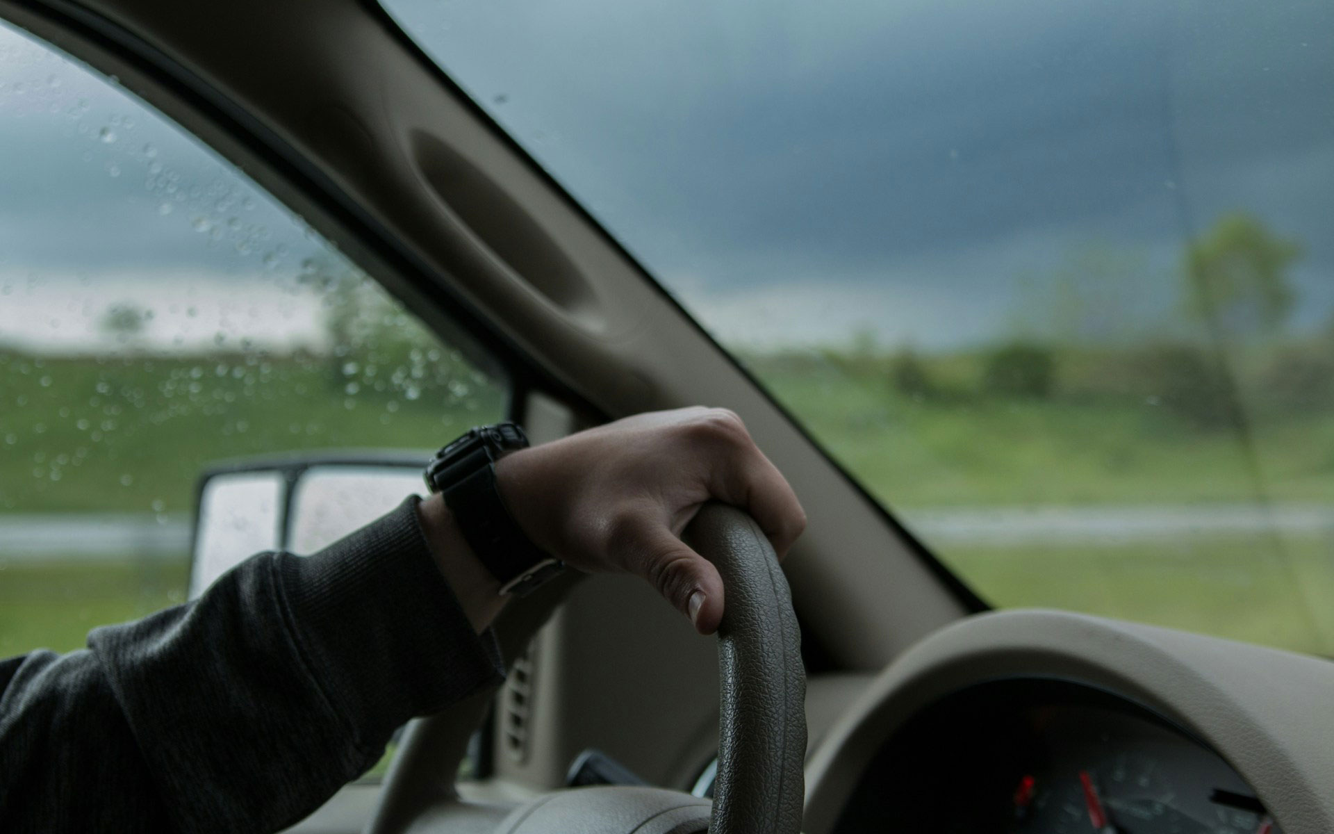 Hand with watch holding a steering wheel