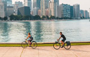 two people riding bikes with the Chicago skyline in the background